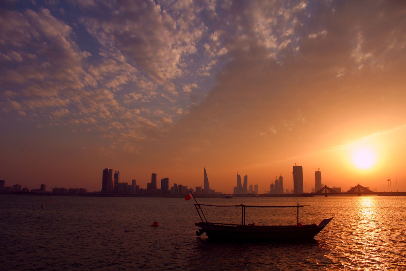 Manama skyline and a traditional dhow at sunset, Bahrain